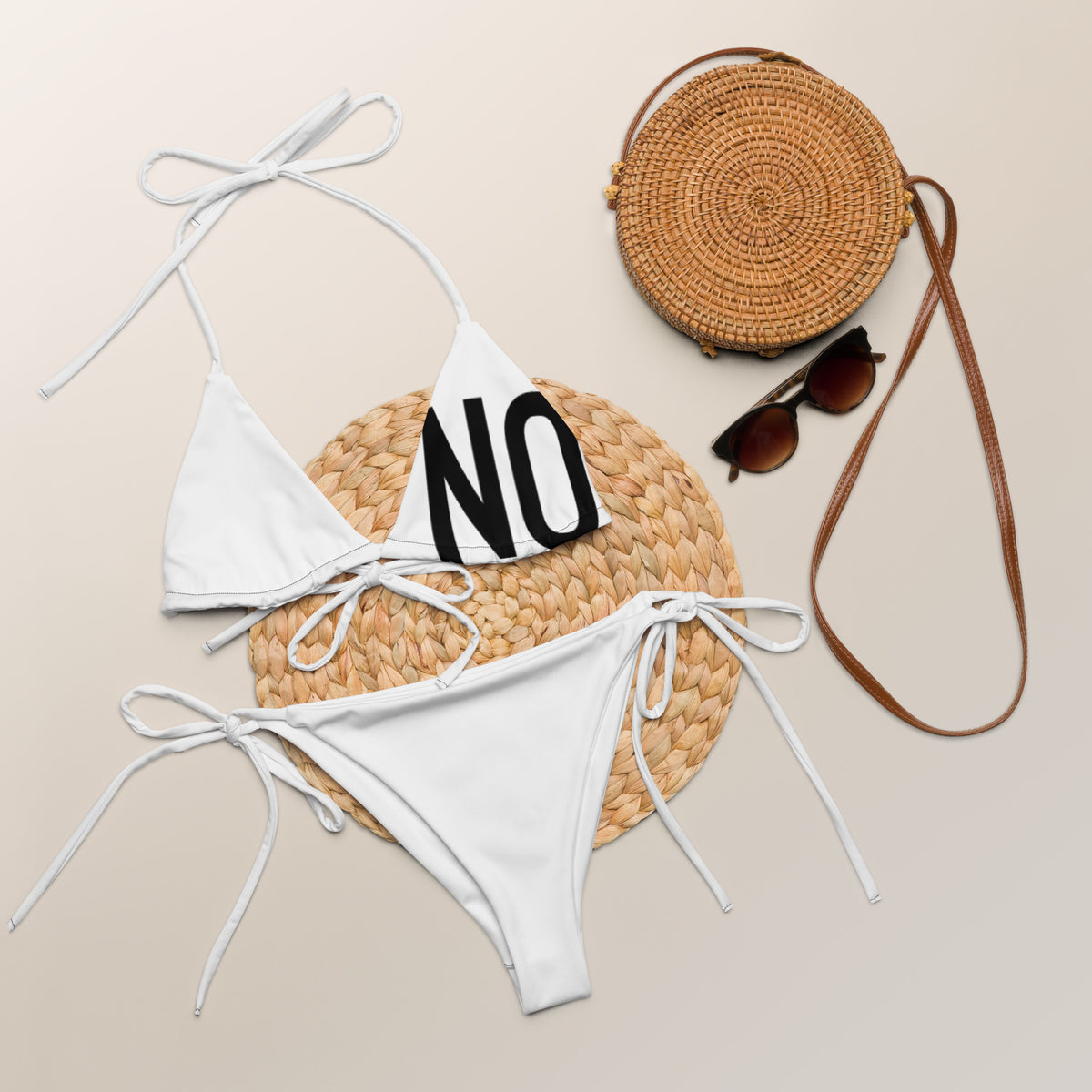 Front facing graphic string bikini swimsuit in color white, featuring the statement 'NO.' in bold black print on the breast cup of the bikini front top. From What Was Said (Statement Apparel + More).