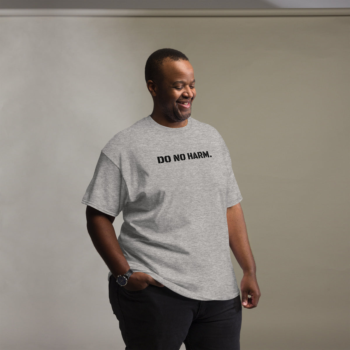 Model is wearing front facing graphic t-shirt in color sport grey, featuring statement 'DO NO HARM', in bold black print. From What Was Said (Statement Apparel + More).