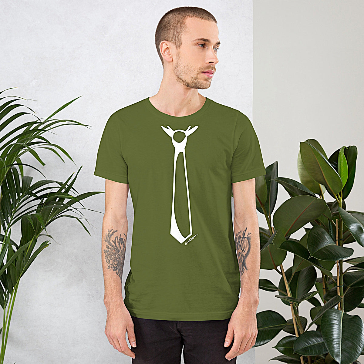 Model wearing front facing graphic T-shirt in color olive green, featuring printed image of men's neck tie, and the written word 'FORMAL', with a strike through it, in white print. From What Was Said (Statement Apparel + More). 