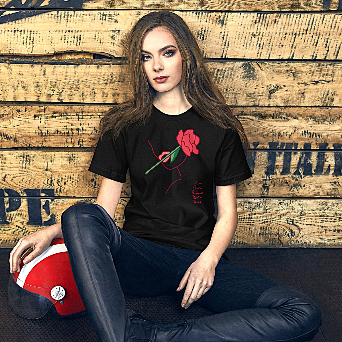 Model is wearing front-facing graphic T-shirt in color black, featuring a woman's profile outlined in red, with a rose in mouth and the words love, passion, romance, devotion, desire, in red print, from What Was Said (Statement Apparel + More).