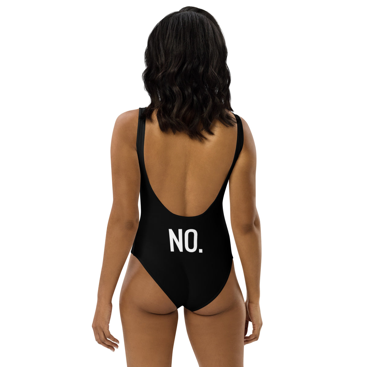 Model is wearing back facing adult graphic one-piece swimsuit in color black, featuring the statement 'NO.' in bold white print. From What Was Said (Statement Apparel + More).