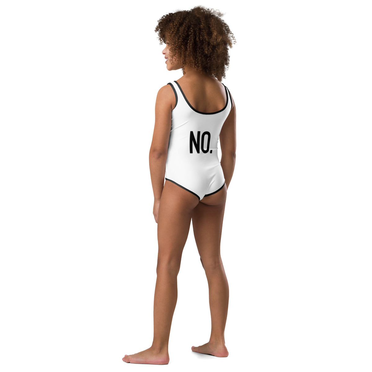 Model is wearing back facing kids graphic one-piece swimsuit in color white with black trim, featuring the statement 'NO.' in bold black print. From What Was Said (Statement Apparel + More).