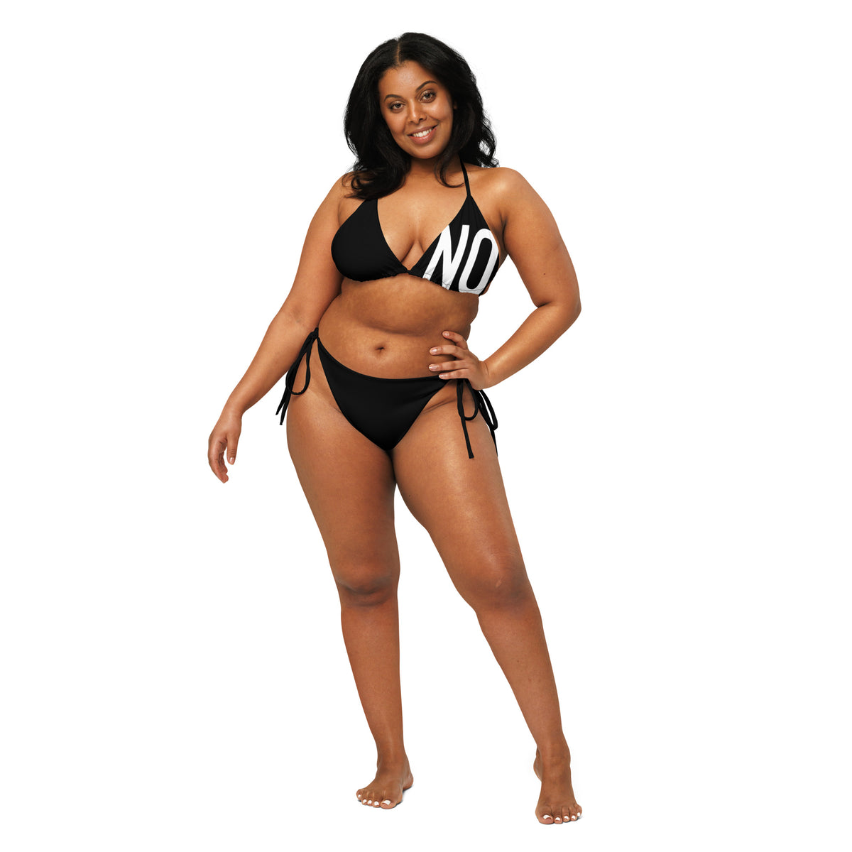 Model wearing front facing graphic  string bikini swimsuit in color black, featuring the statement 'NO.' in bold white print on the breast cup of the bikini front top. From What Was Said (Statement Apparel + More).