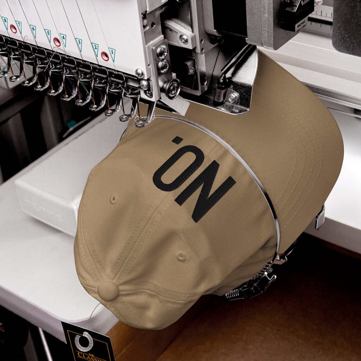 Product detail of embroidered stitching on front facing graphic dad hat in color khaki, featuring the statement 'NO' in bold black embroidery. From What Was Said (Statement Apparel + More).