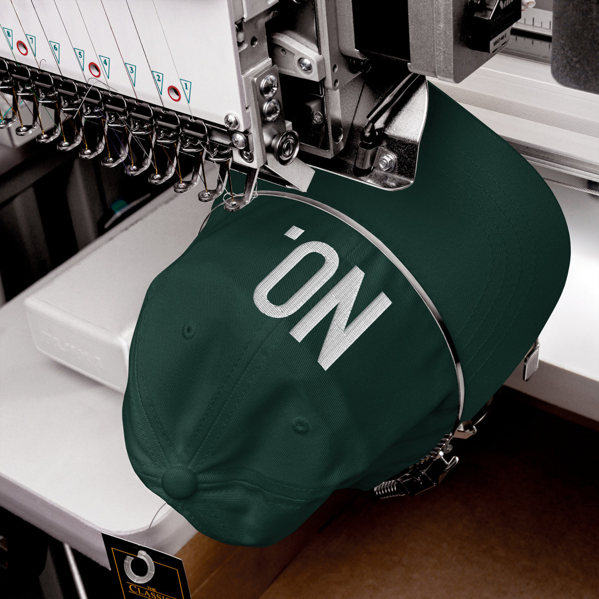 Product detail of embroidered stitching on front facing graphic dad hat in color spruce green, featuring the statement 'NO' in bold white embroidery. From What Was Said (Statement Apparel + More).