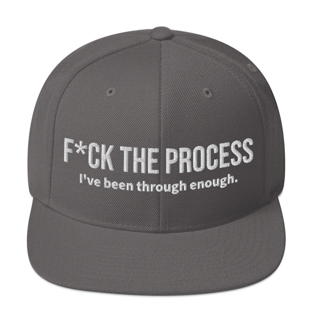 Front facing graphic snapback hat in color dark grey, featuring the statement 'FUCK THE PROCESS, I've Been Through Enough,' in bold white embroidery. From What Was Said (Statement Apparel + More).