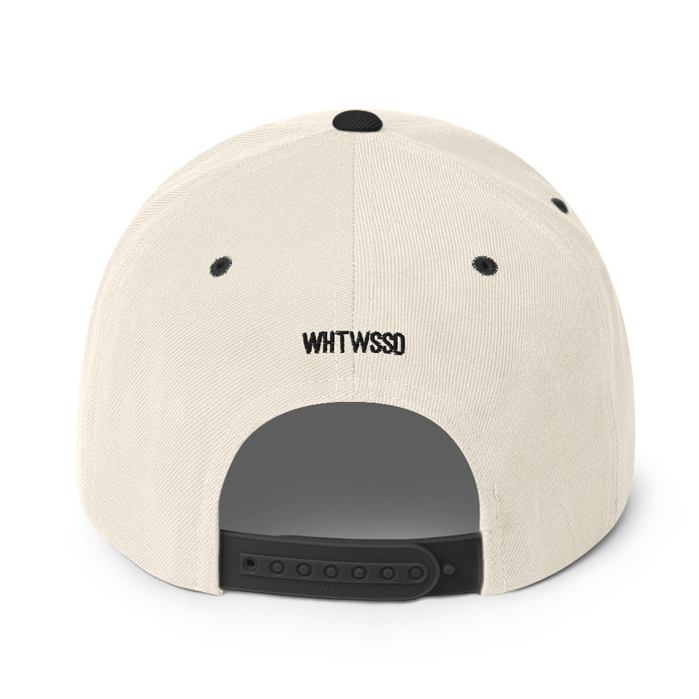 Product details on back facing graphic snapback hat in color natural and black, featuring close up view of hats plastic snap closure and brand acronym WHTWSSD in black embroidery. From What Was Said (Statement Apparel + More).