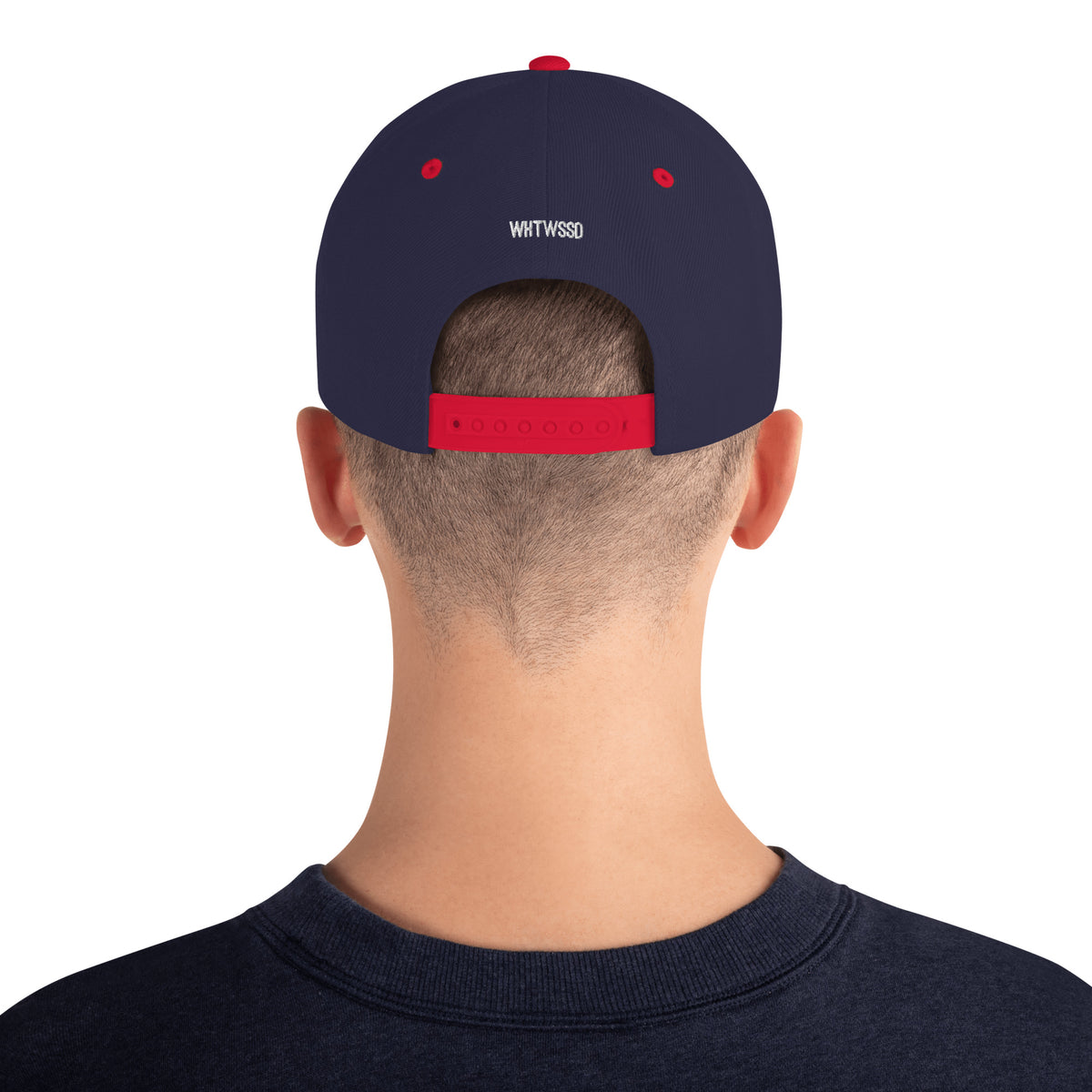 Model is wearing back facing graphic snapback hat in color navy and red, featuring view of hats plastic snap closure and brand acronym WHTWSSD in white embroidery. From What Was Said (Statement Apparel + More).