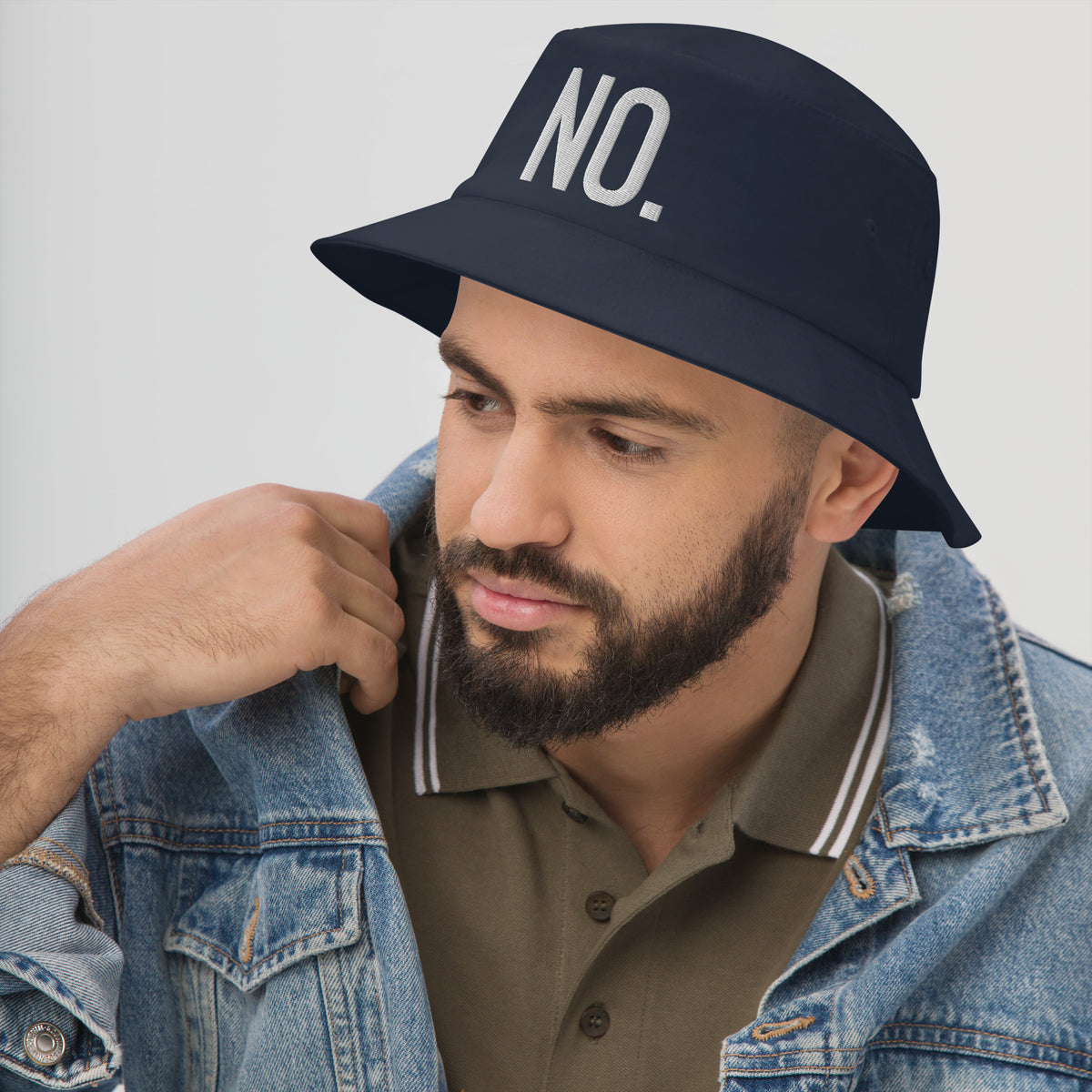 Model is wearing left front facing graphic bucket hat in color navy blue, featuring the statement 'NO.' in bold white embroidery. From What Was Said (Statement Apparel + More).