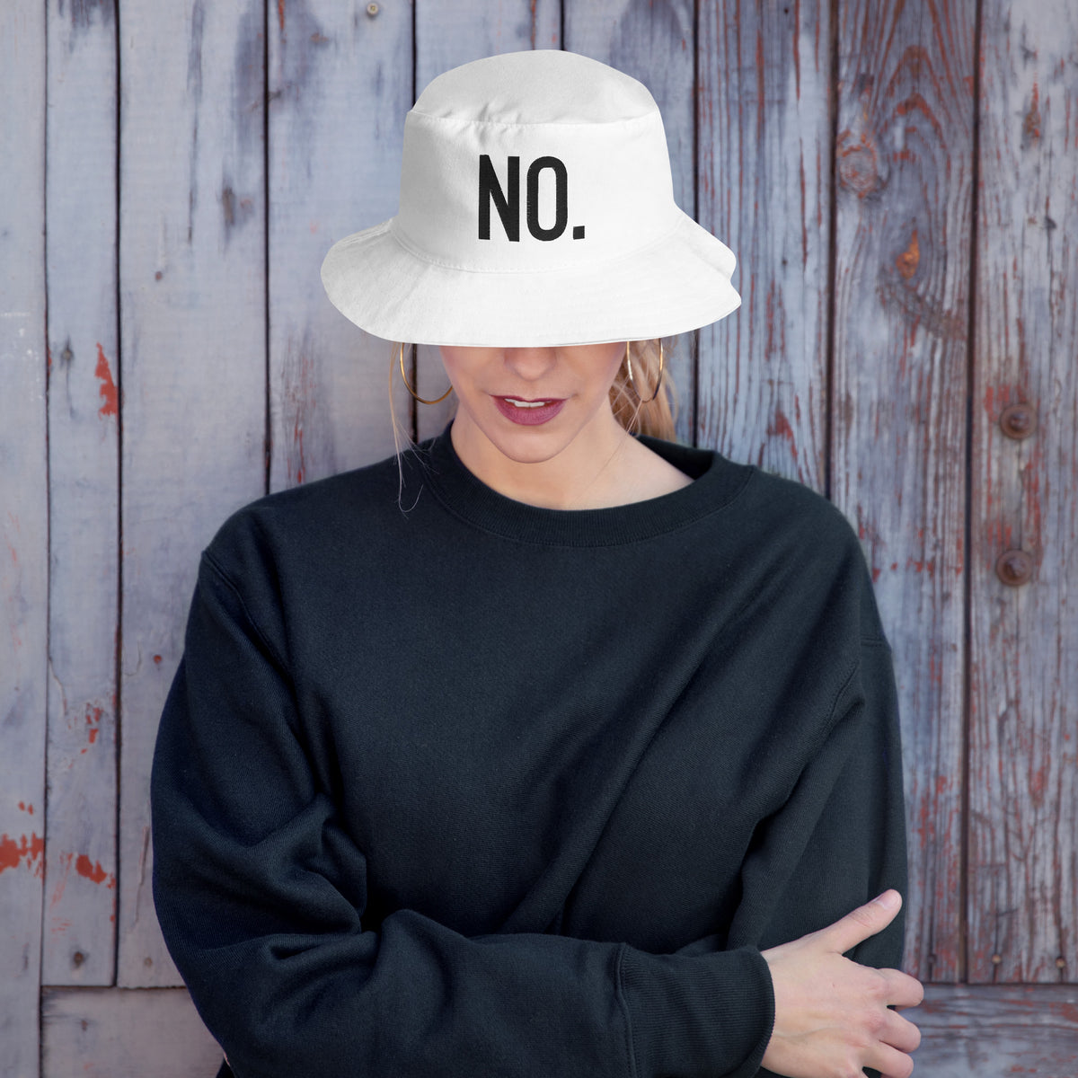 Model wearing front facing graphic bucket hat in color white, featuring the statement 'NO.' in bold black embroidery. From What Was Said (Statement Apparel + More).