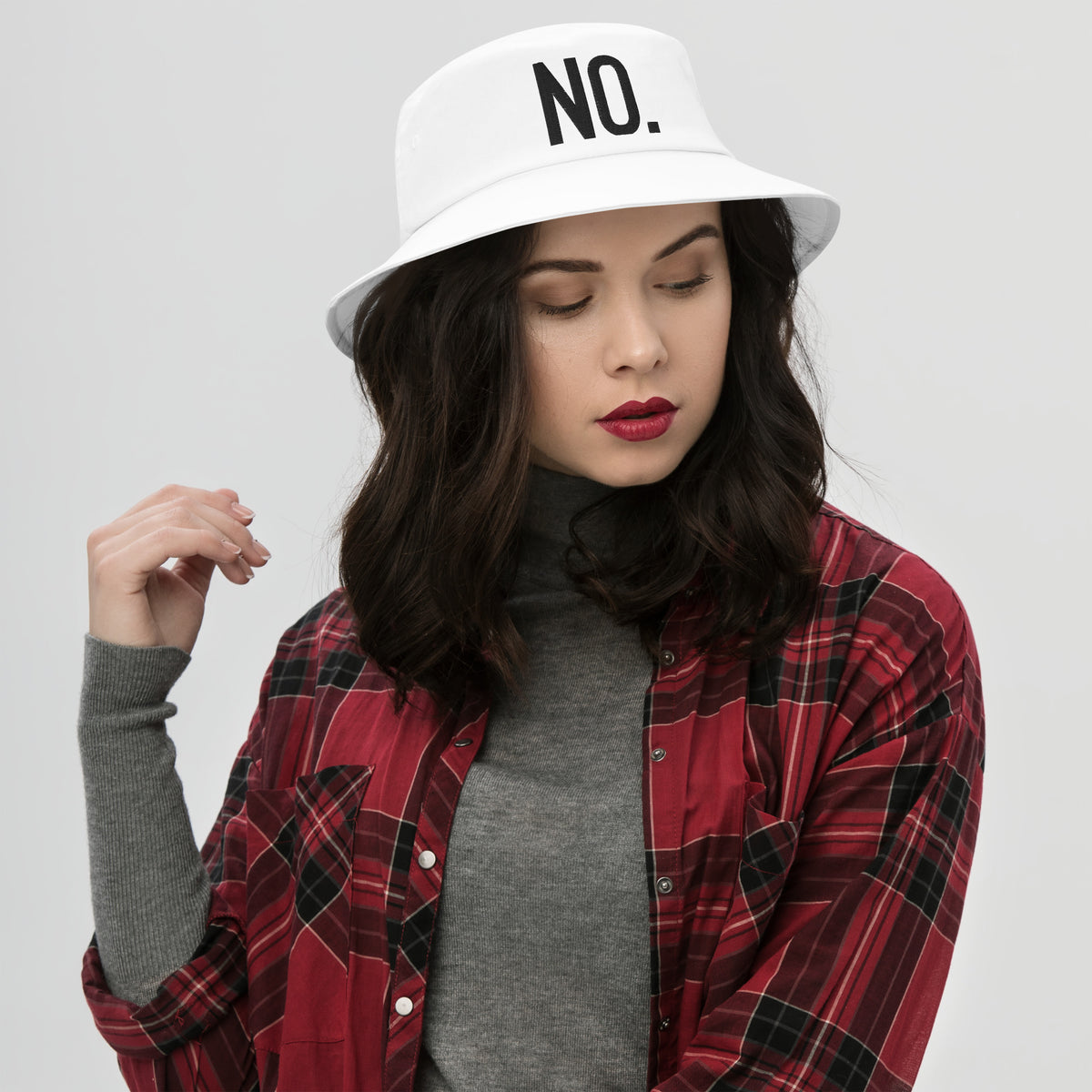 Model wearing front facing graphic bucket hat in color white, featuring the statement 'NO.' in bold black embroidery. From What Was Said (Statement Apparel + More).