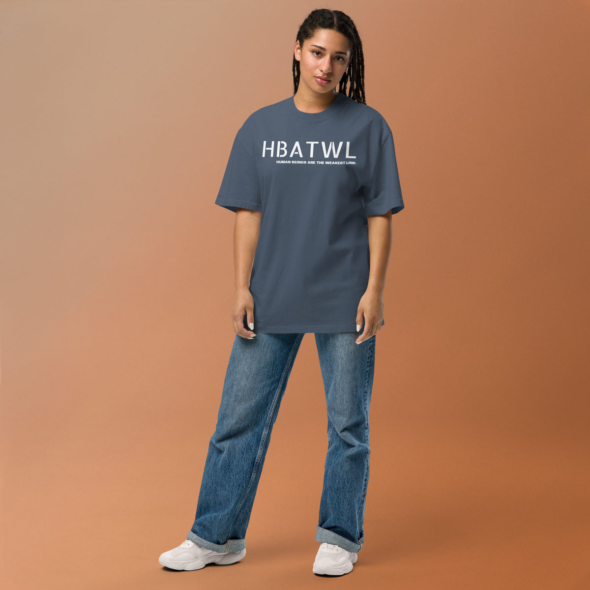 Model wearing front facing oversized fit graphic t-shirt in color faded indigo, featuring initialism HBATWL, and statement 'HUMAN BEINGS ARE THE WEAKEST LINK', in bold white print. From What Was Said (Statement Apparel + More).