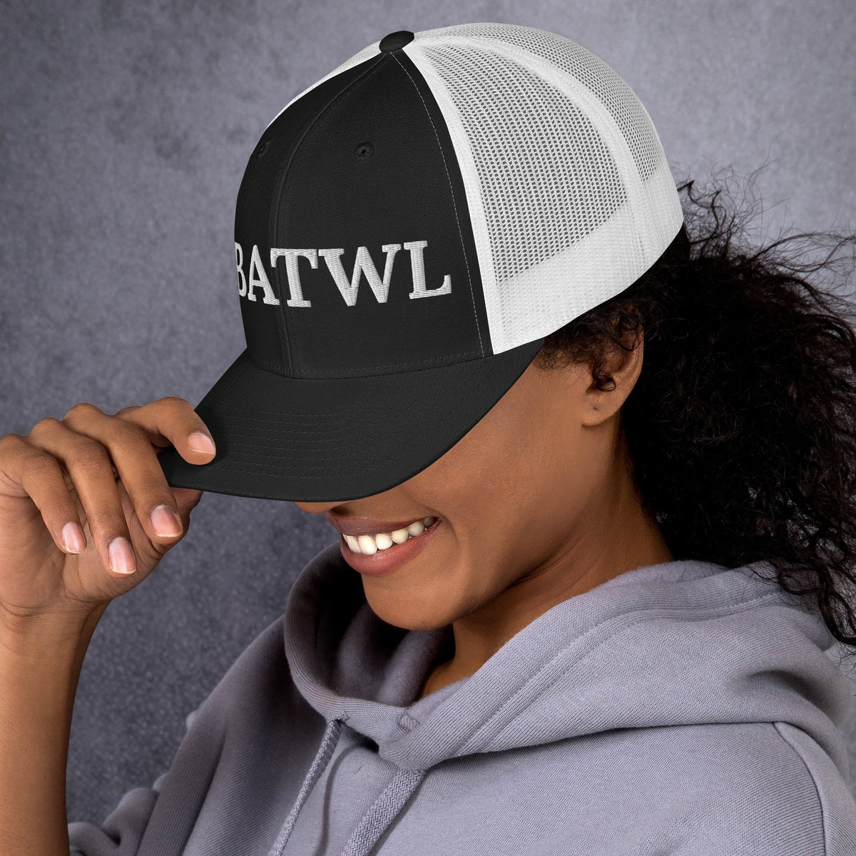 Model is wearing left front facing graphic trucker hat in color black and white, featuring the initialism 'HBATWL', from What Was Said (Statement Apparel + More).