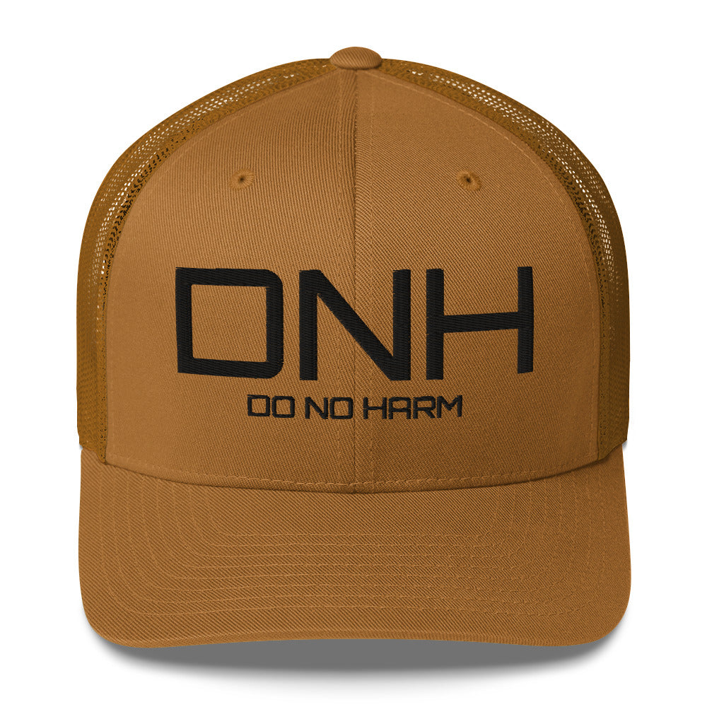 Front facing graphic trucker hat in color caramel, featuring the initialism 'DNH', and the statement 'DO NO HARM,' in bold black embroidery. From What Was Said (Statement Apparel + More).