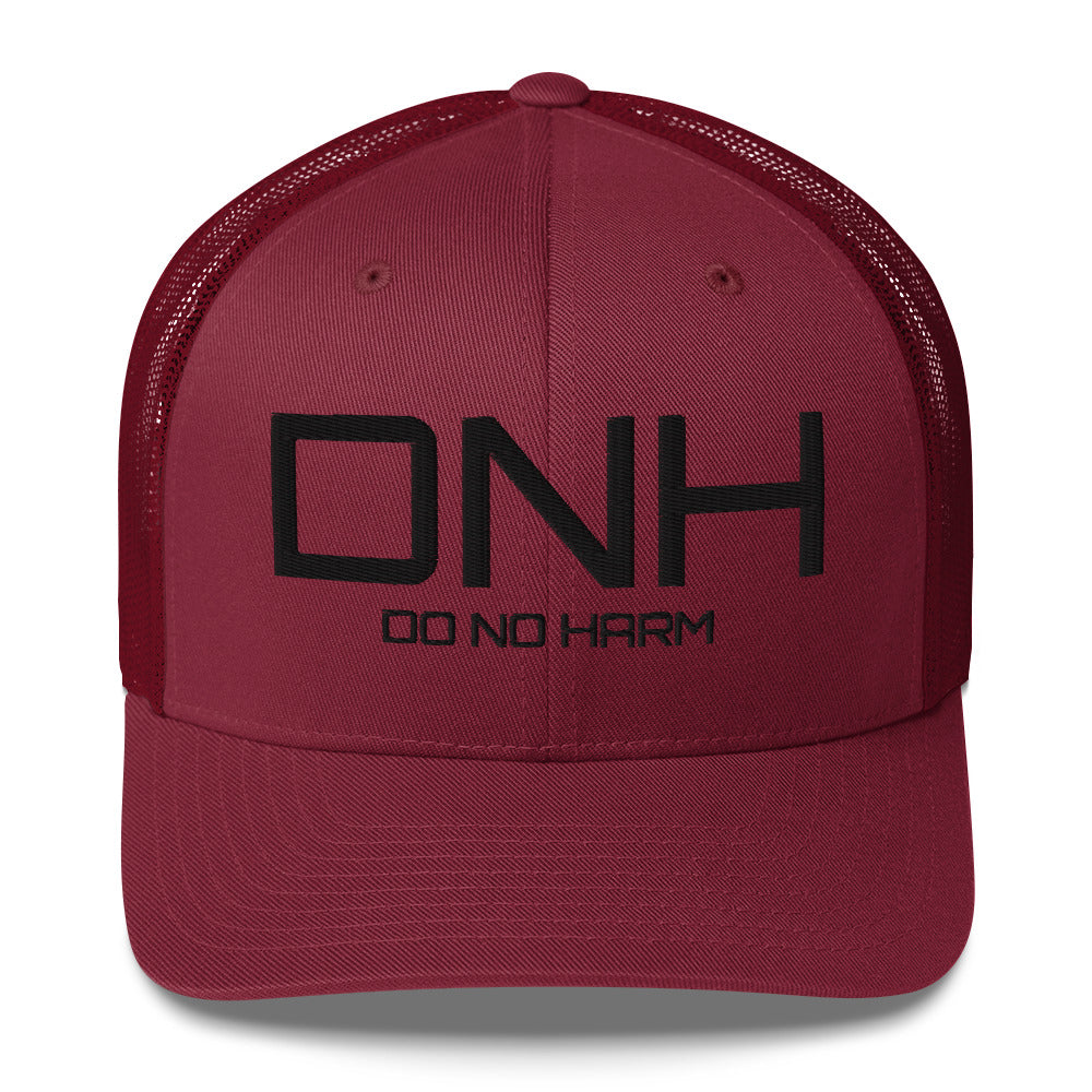 Front facing graphic trucker hat in color maroon red, featuring the initialism 'DNH', and the statement 'DO NO HARM,' in bold black embroidery. From What Was Said (Statement Apparel + More).
