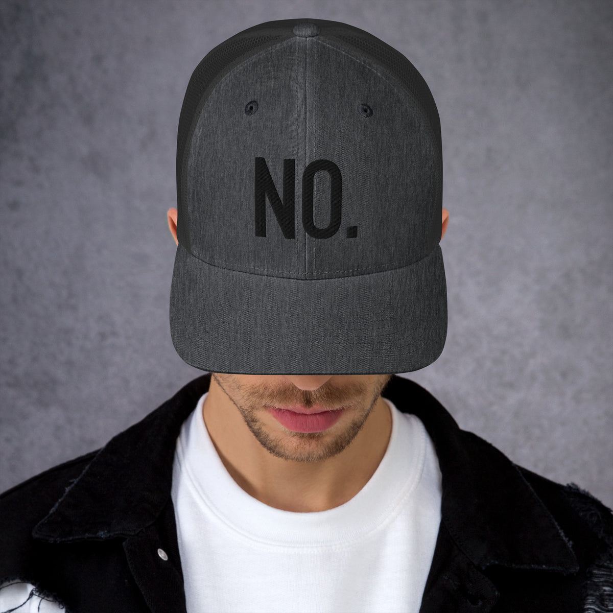 Model is wearing front facing graphic trucker hat in color dark heather grey, featuring the statement 'NO.' in bold black embroidery. From What Was Said (Statement Apparel + More).