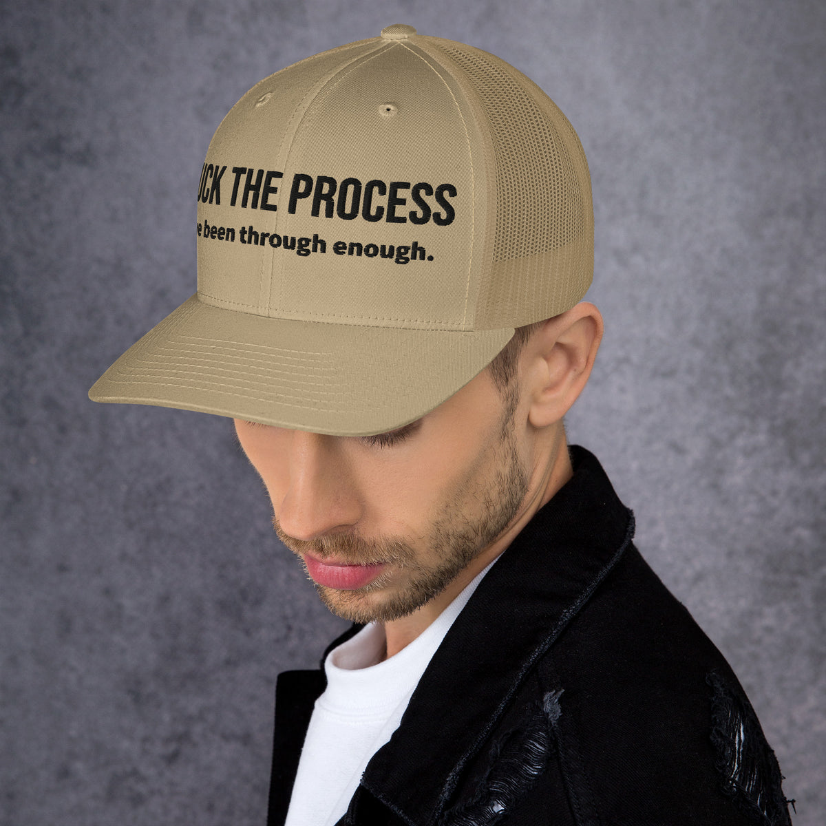 Model is wearing left front facing graphic trucker hat in color khaki, featuring the statement 'FUCK THE PROCESS, I've Been Through Enough,' in bold black embroidery. From What Was Said (Statement Apparel + More).