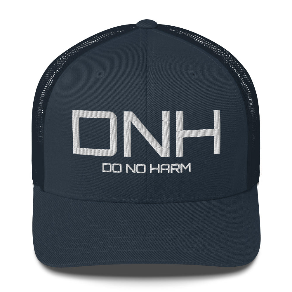 Front facing graphic trucker hat in color navy blue, featuring the initialism 'DNH', and the statement 'DO NO HARM,' in bold white embroidery. From What Was Said (Statement Apparel + More).
