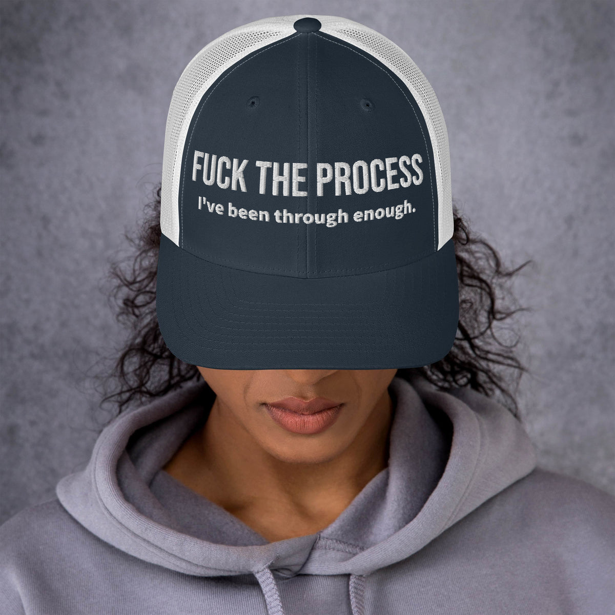 Model wearing front facing graphic trucker hat in color navy blue and white, featuring the statement 'FUCK THE PROCESS, I've Been Through Enough,' in bold white embroidery. From What Was Said (Statement Apparel + More).