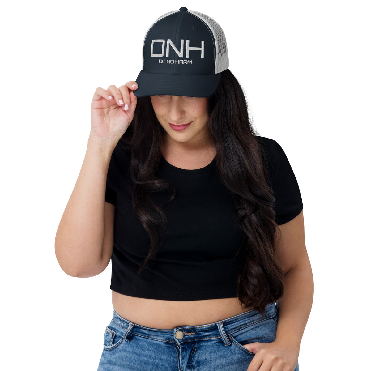 Model is wearing front facing graphic trucker hat in color navy blue and white, featuring the initialism 'DNH', and the statement 'DO NO HARM,' in bold white embroidery. From What Was Said (Statement Apparel + More).
