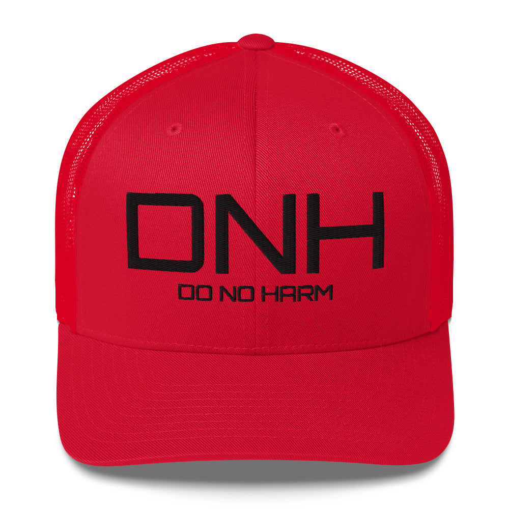 Front facing graphic trucker hat in color red, featuring the initialism 'DNH', and the statement 'DO NO HARM,' in bold black embroidery. From What Was Said (Statement Apparel + More).