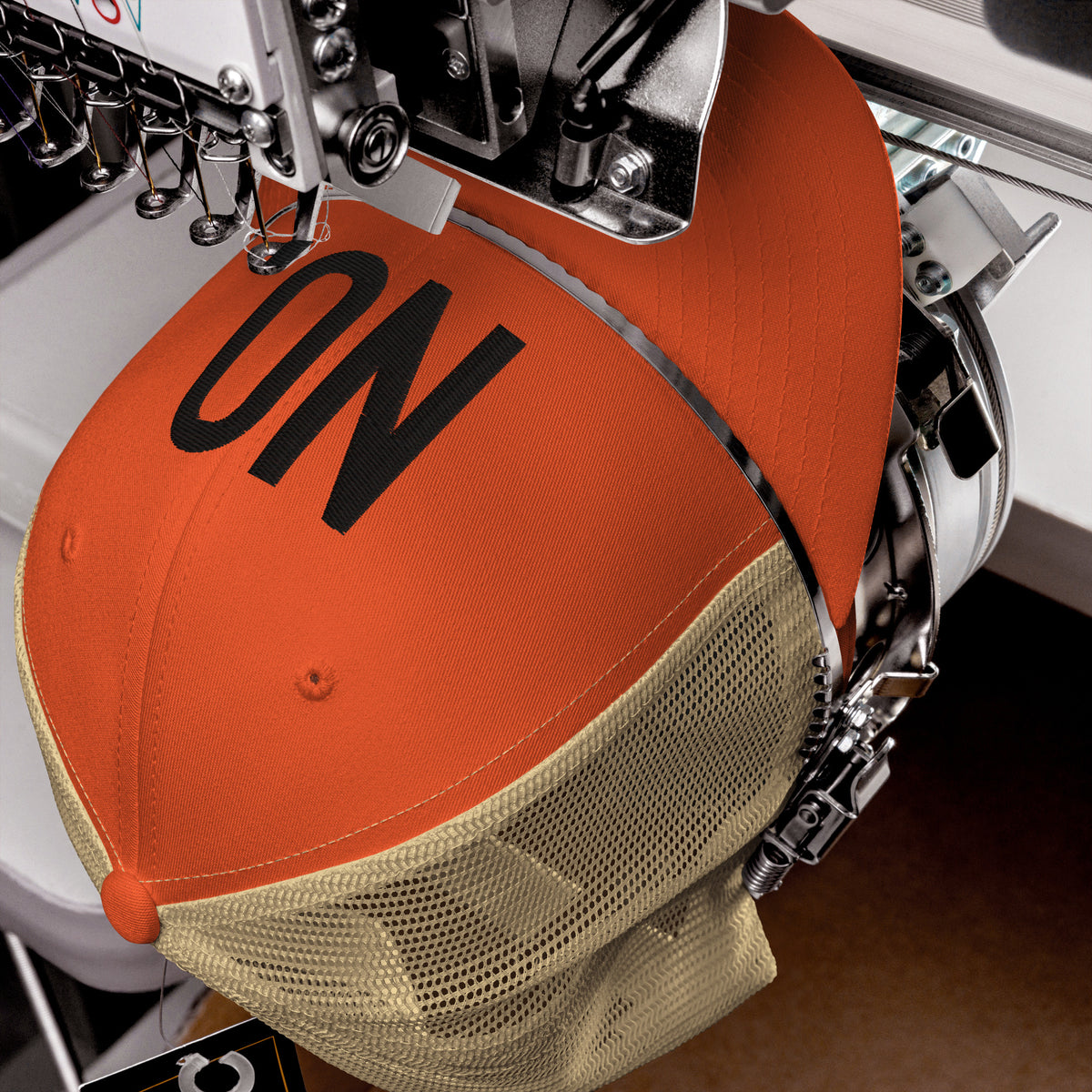 Product detail of embroidered stitching on front facing graphic trucker hat in color rustic orange and khaki, featuring the statement 'NO' in bold black embroidery. From What Was Said (Statement Apparel + More).