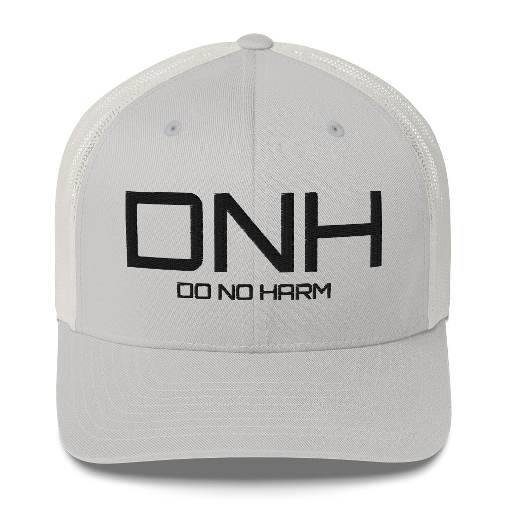 Front facing graphic trucker hat in color silver light grey, featuring the initialism 'DNH', and the statement 'DO NO HARM,' in bold black embroidery. From What Was Said (Statement Apparel + More).