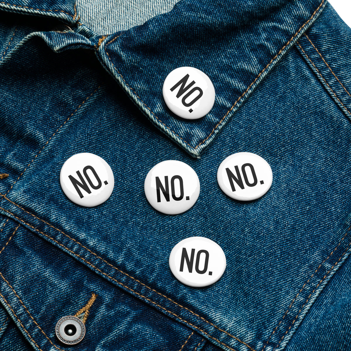 Front facing graphic pin buttons, pinned to a blue jean jacket. Buttons are in color white and size 1.25 inches. Featuring the statement NO in bold black print. From What Was Said (Statement Apparel + More). 