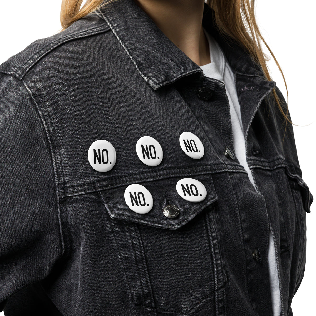 Model is wearing front facing graphic pin buttons, pinned to a jean jacket. Buttons are in color white and size 1.25 inches. Featuring the statement NO, in bold black print. From What Was Said (Statement Apparel + More). 
