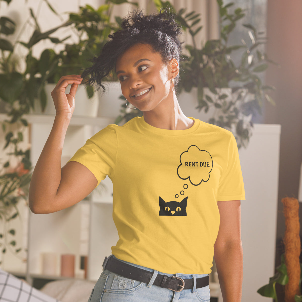Model wearing front facing graphic T-shirt in color daisy yellow, featuring printed image of cat with thought bubble, and the words 'RENT DUE', inside the bubble in black print. From What Was Said (Statement Apparel + More).