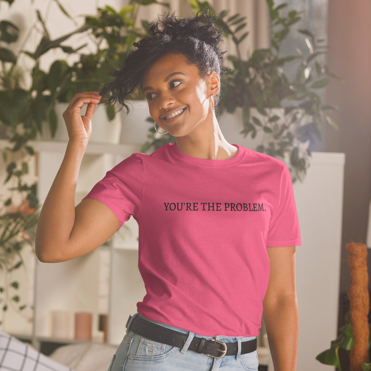 Model wearing front facing graphic t-shirt in color heliconia pink featuring statement, 'YOU'RE THE PROBLEM', in bold black print. From What Was Said (Statement Apparel + More).
