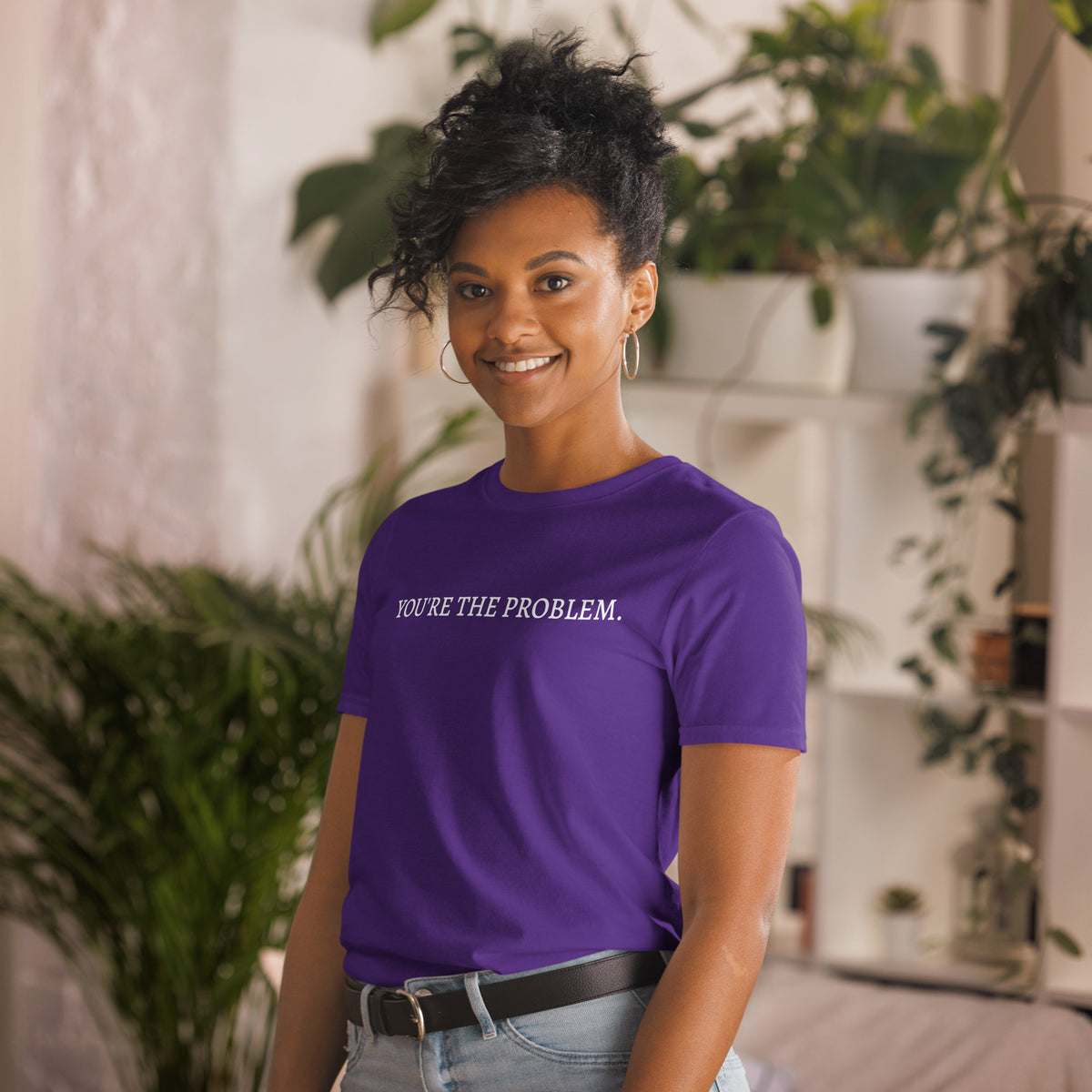 Model is wearing left front facing graphic t-shirt in color purple featuring statement, 'YOU'RE THE PROBLEM', in bold white print. From What Was Said (Statement Apparel + More).