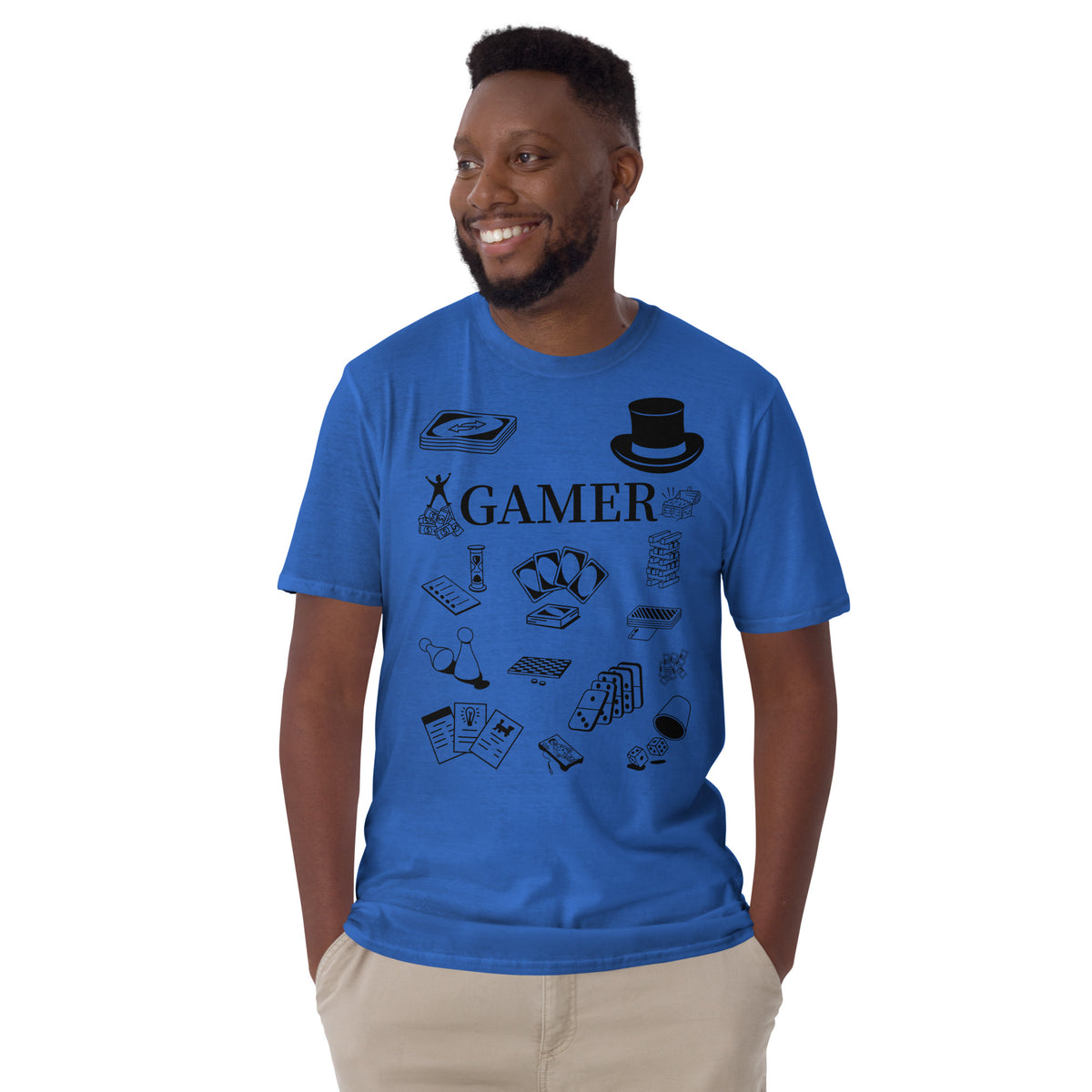 Model is standing against a white background wearing front facing graphic T-shirt in color royal blue, featuring printed image of various classic board game pieces and the word 'GAMER' in black print, from What Was Said (Statement Apparel + More). 