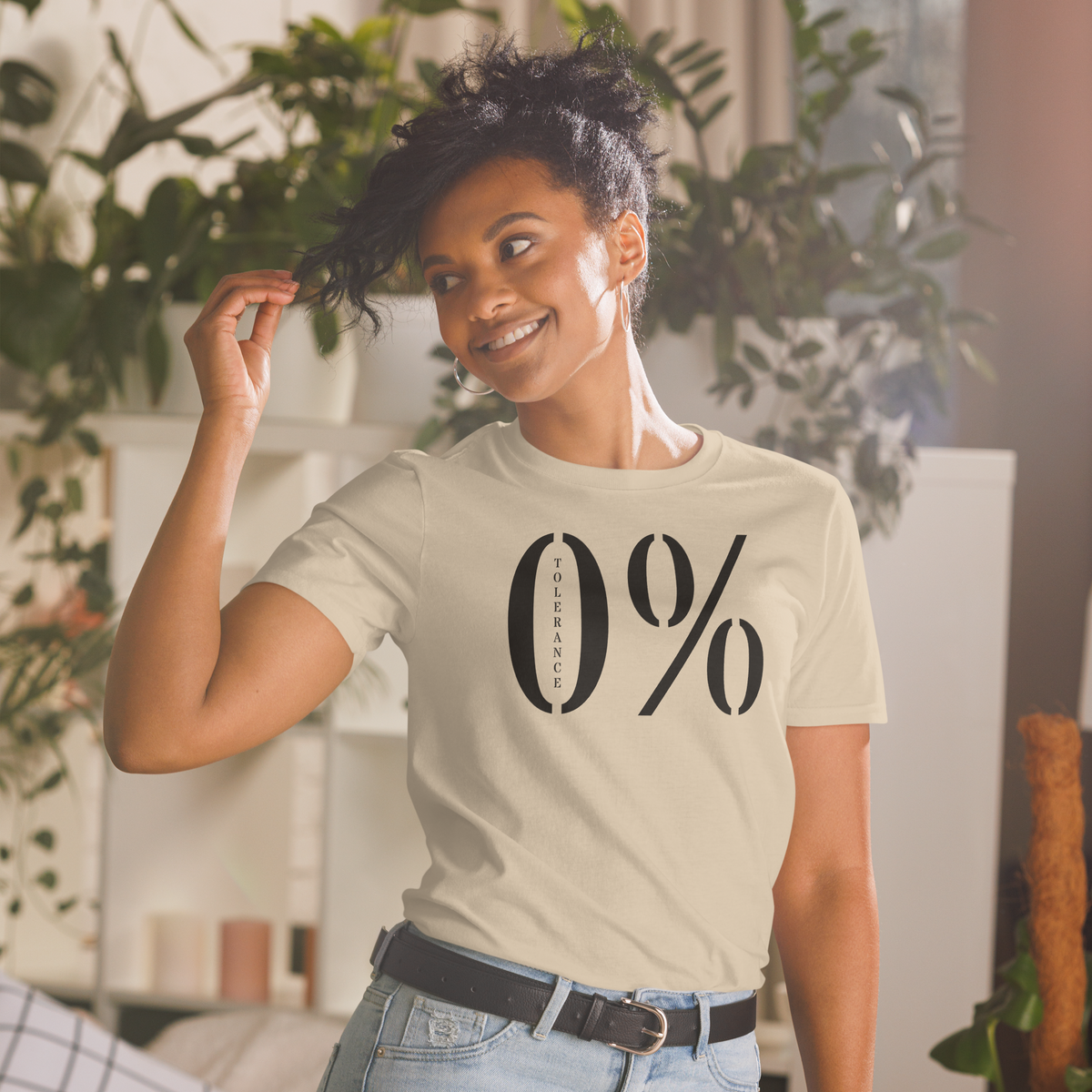 Model is wearing front facing graphic t-shirt in color sand featuring a large zero percent symbol and the written word, 'TOLERANCE', in bold black print. From What Was Said (Statement Apparel + More).