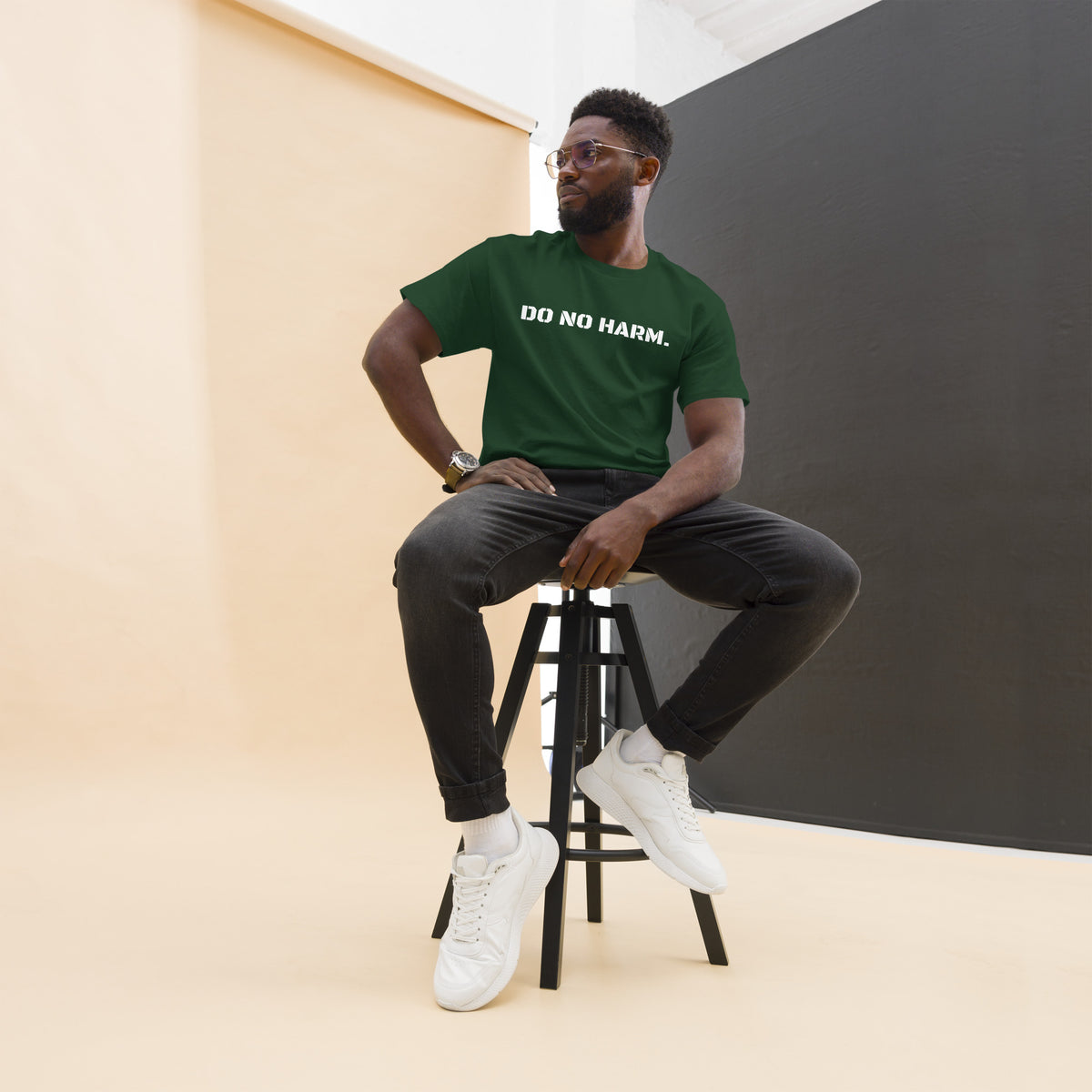 Model is wearing front facing graphic t-shirt in color forest green, featuring statement 'DO NO HARM', in bold white print. From What Was Said (Statement Apparel + More).