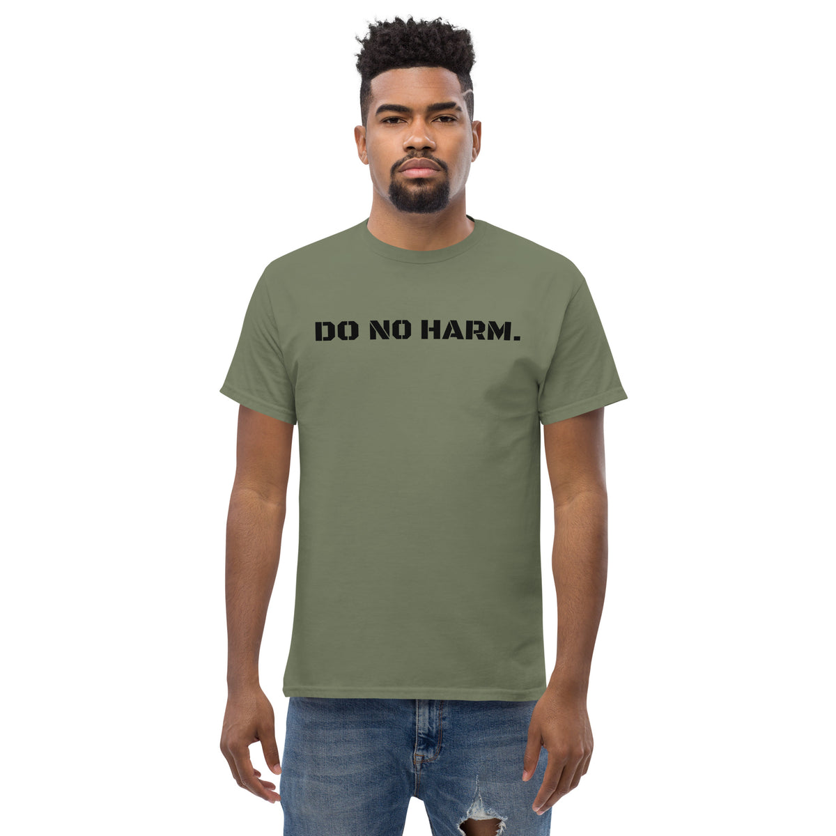 Model is wearing front facing graphic t-shirt in color military green, featuring statement 'DO NO HARM', in bold black print. From What Was Said (Statement Apparel + More).
