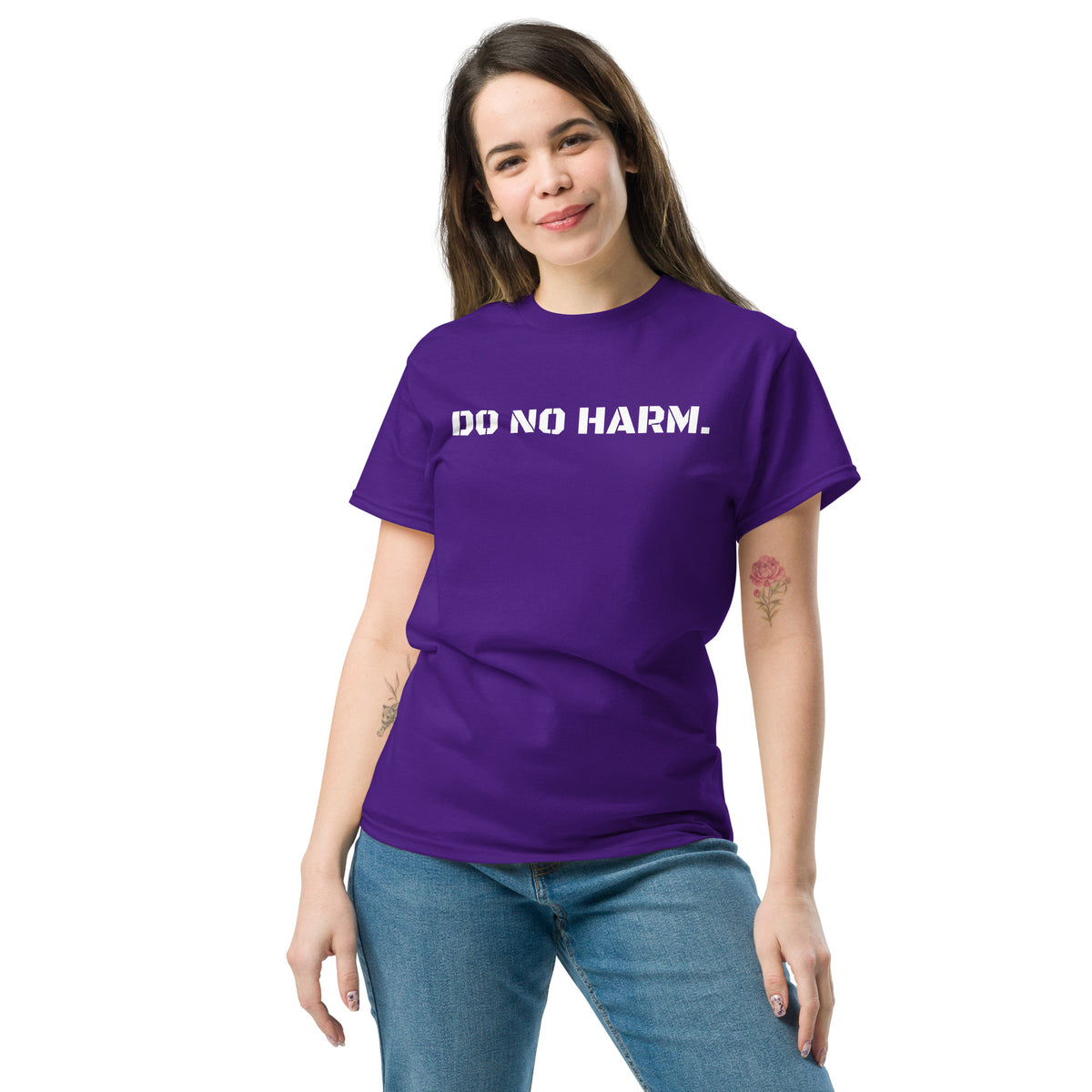 Model is wearing front facing graphic t-shirt in color purple, featuring statement 'DO NO HARM', in bold white print. From What Was Said (Statement Apparel + More).