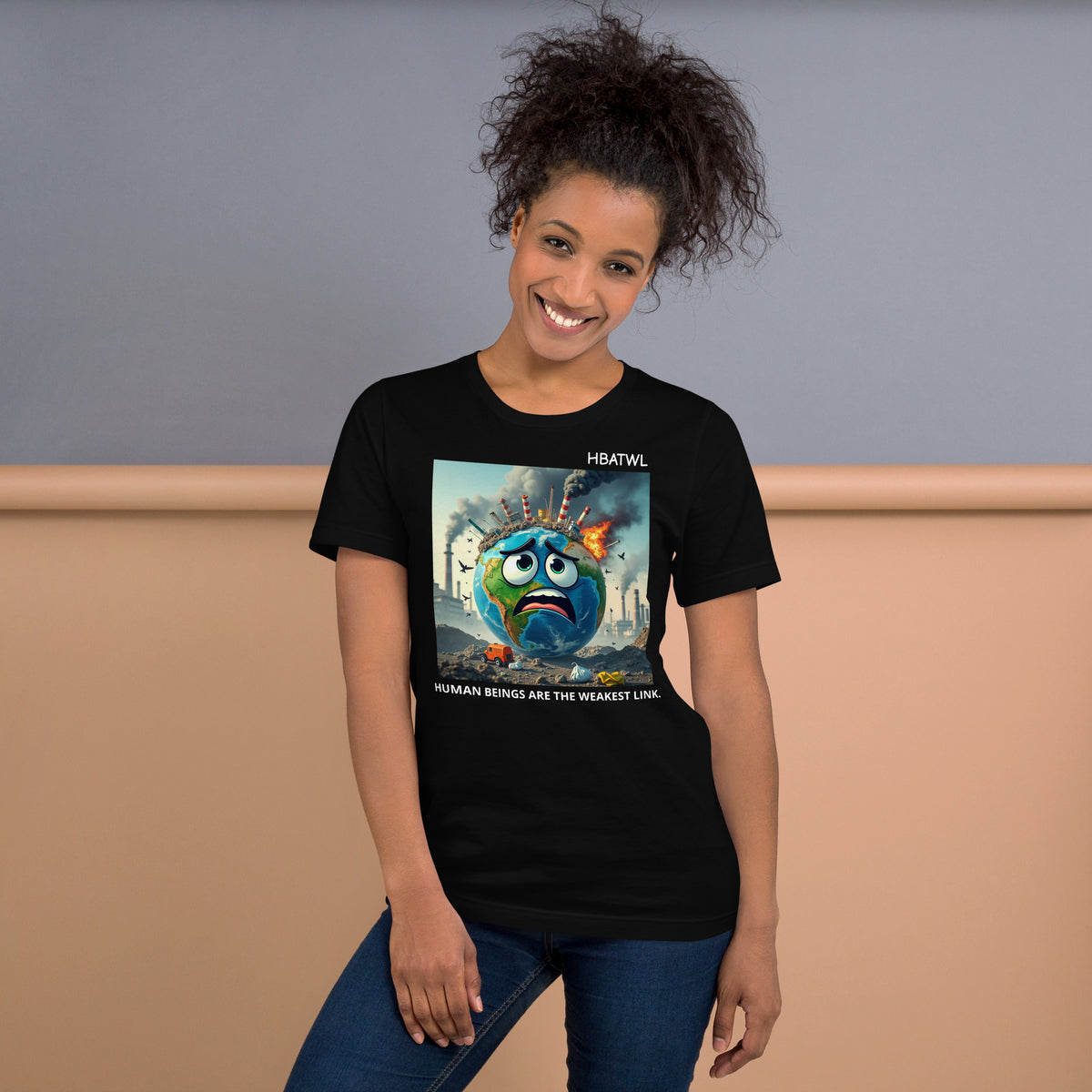 Model is wearing front facing graphic T-shirt in color black featuring an animated earth with facial expression of concern over being negatively effected by human pollution. Bold statement on the shirt reads, 'Human Beings Are The Weakest link.', in white print. From What Was Said (Statement Apparel + More). 