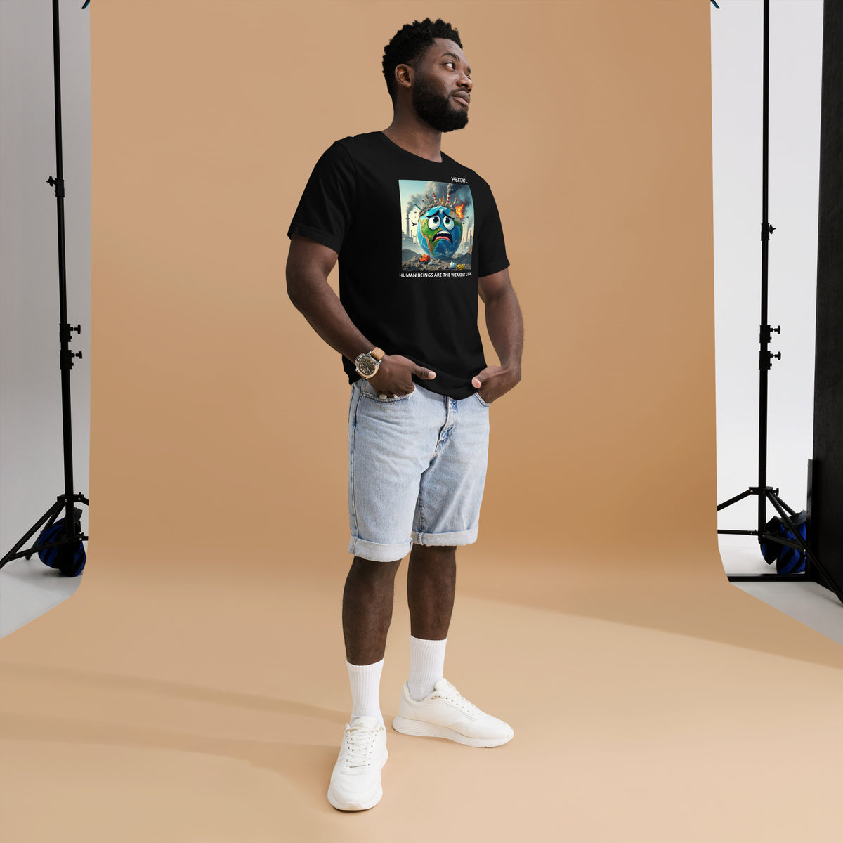 Model is wearing front facing graphic T-shirt in color black featuring an animated earth with facial expression of concern over being negatively effected by human pollution. Bold statement on the shirt reads, 'Human Beings Are The Weakest link.', in white print. From What Was Said (Statement Apparel + More). 