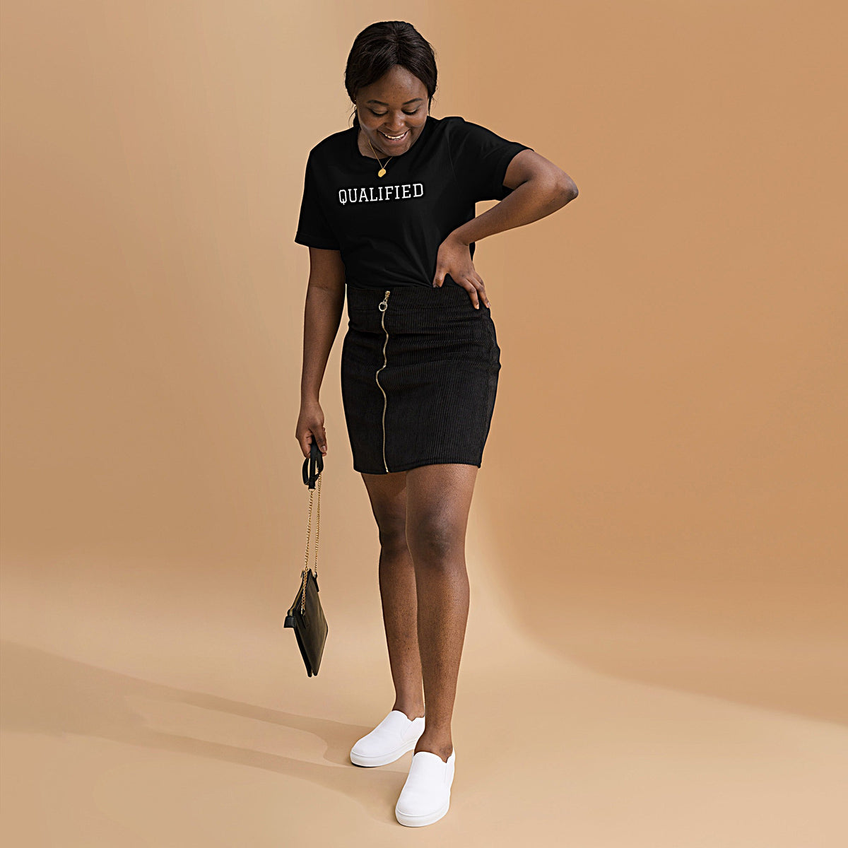 Model wearing front-facing graphic T-shirt in color black, featuring the word 'QUALIFIED' in bold white print, from What Was Said (Statement Apparel + More).