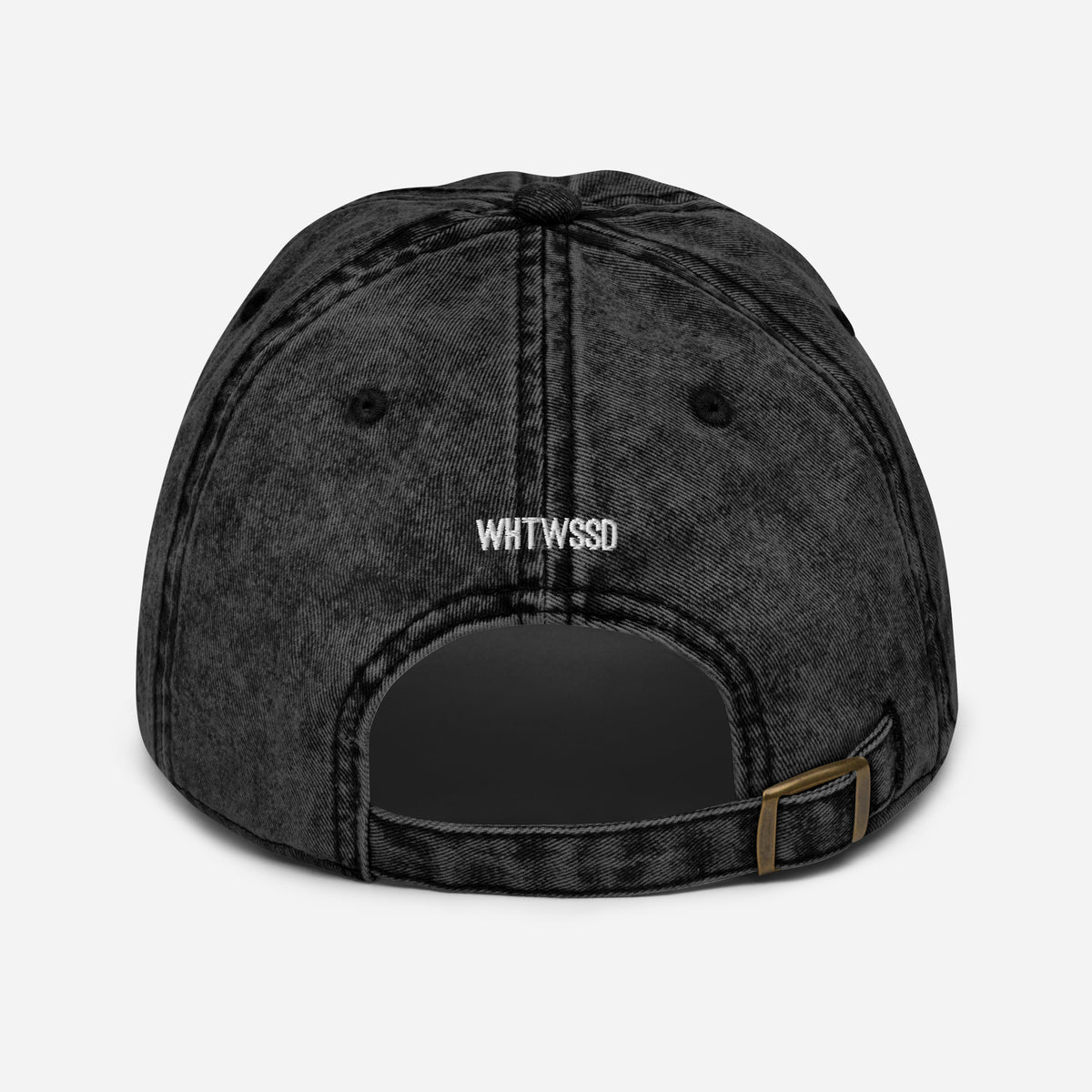 Product details on back facing vintage graphic cotton twill cap in color black wash, featuring close up view of hats metal snap buckle closure and brand acronym WHTWSSD in white embroidery. From What Was Said (Statement Apparel + More).